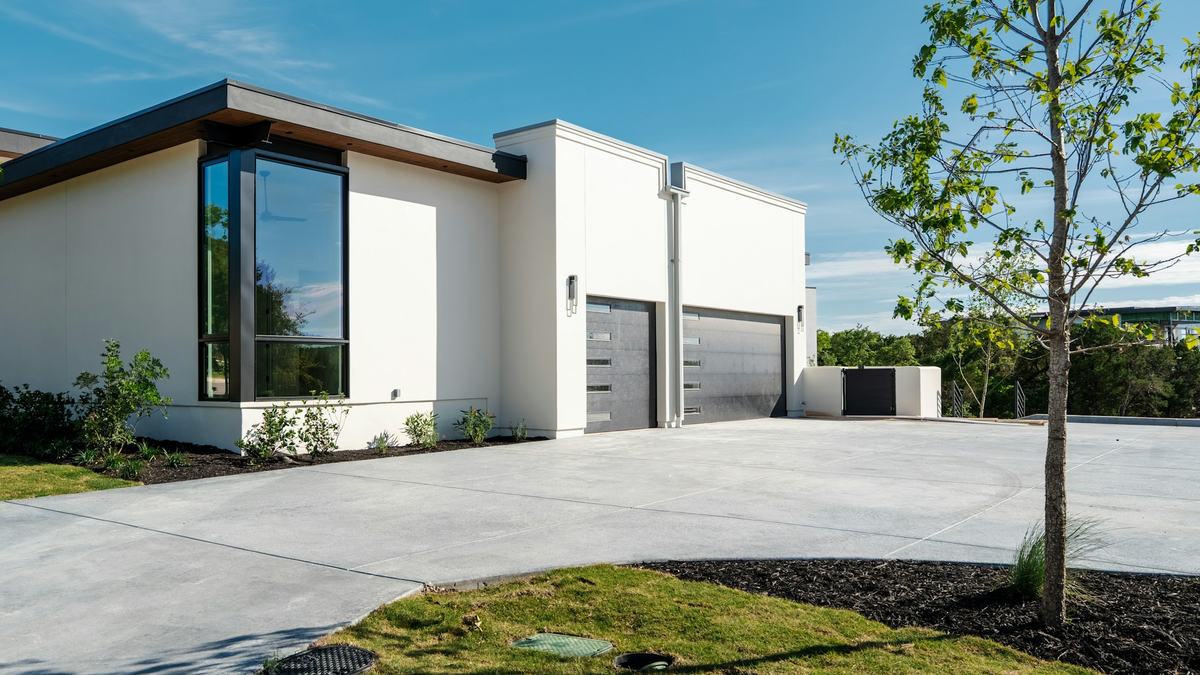 Wide poured concrete driveway leading to a modern home's two-car garage