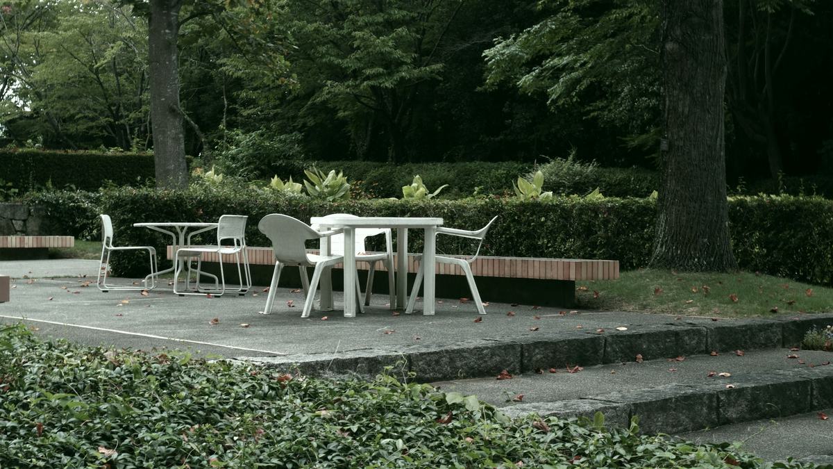 Concrete patio with a table and chairs surrounded by garden planting